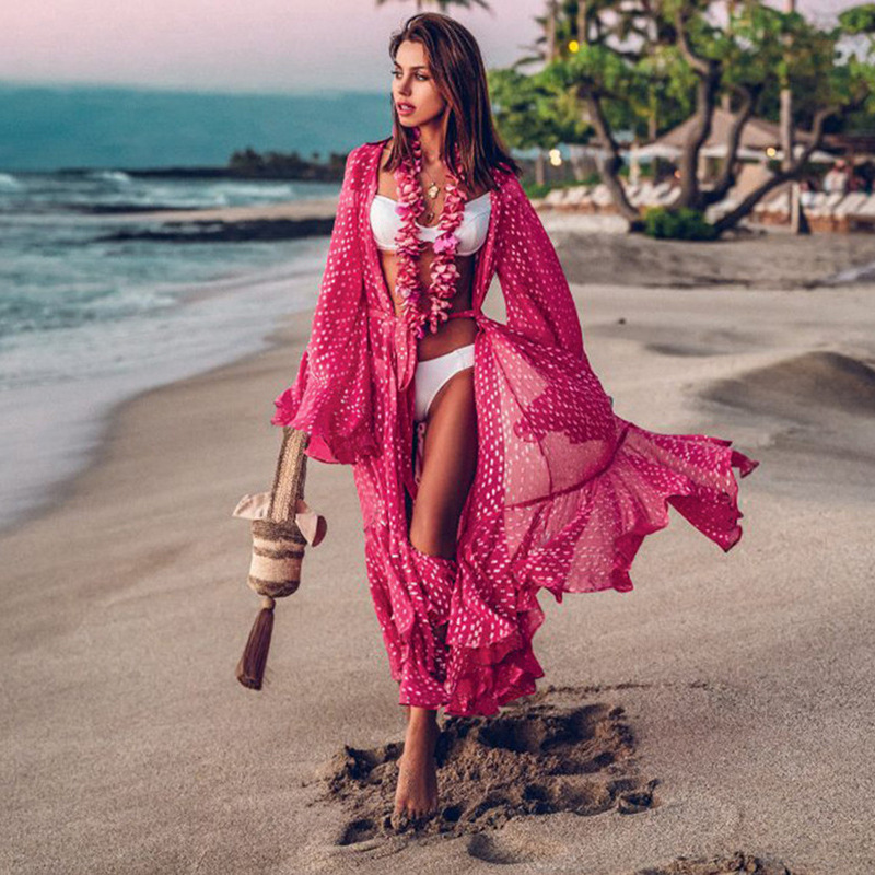 Woman in rose colored cover-up walking on the beach